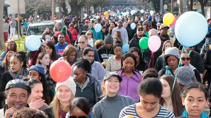 Smiling marchers of every age walk among balloons