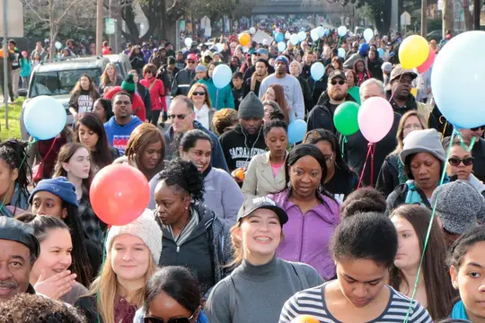Smiling marchers of every age walk among balloons