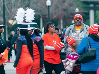 A marching band member in a plumed hat stands with families
