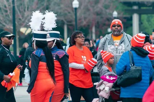 A marching band member in a plumed hat stands with families