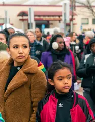 A young girl and a woman stand in the crowd before the march