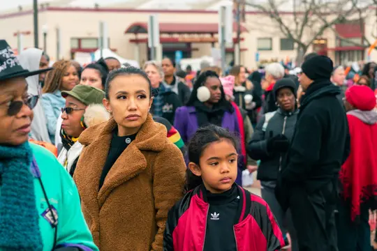 A young girl and a woman stand in the crowd before the march